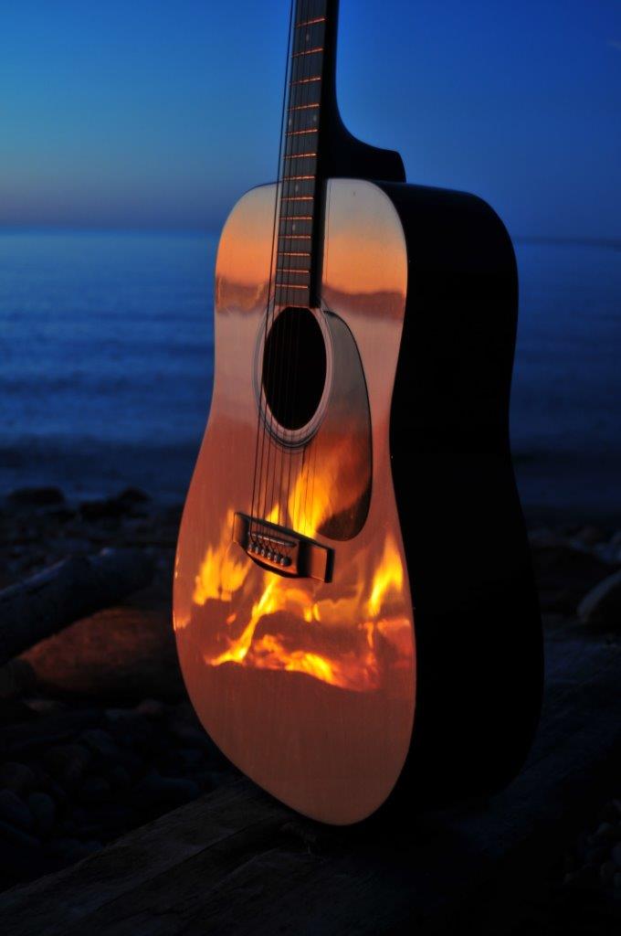 Acoustic guitar on the beach with reflection of campfire - example of low-light photography