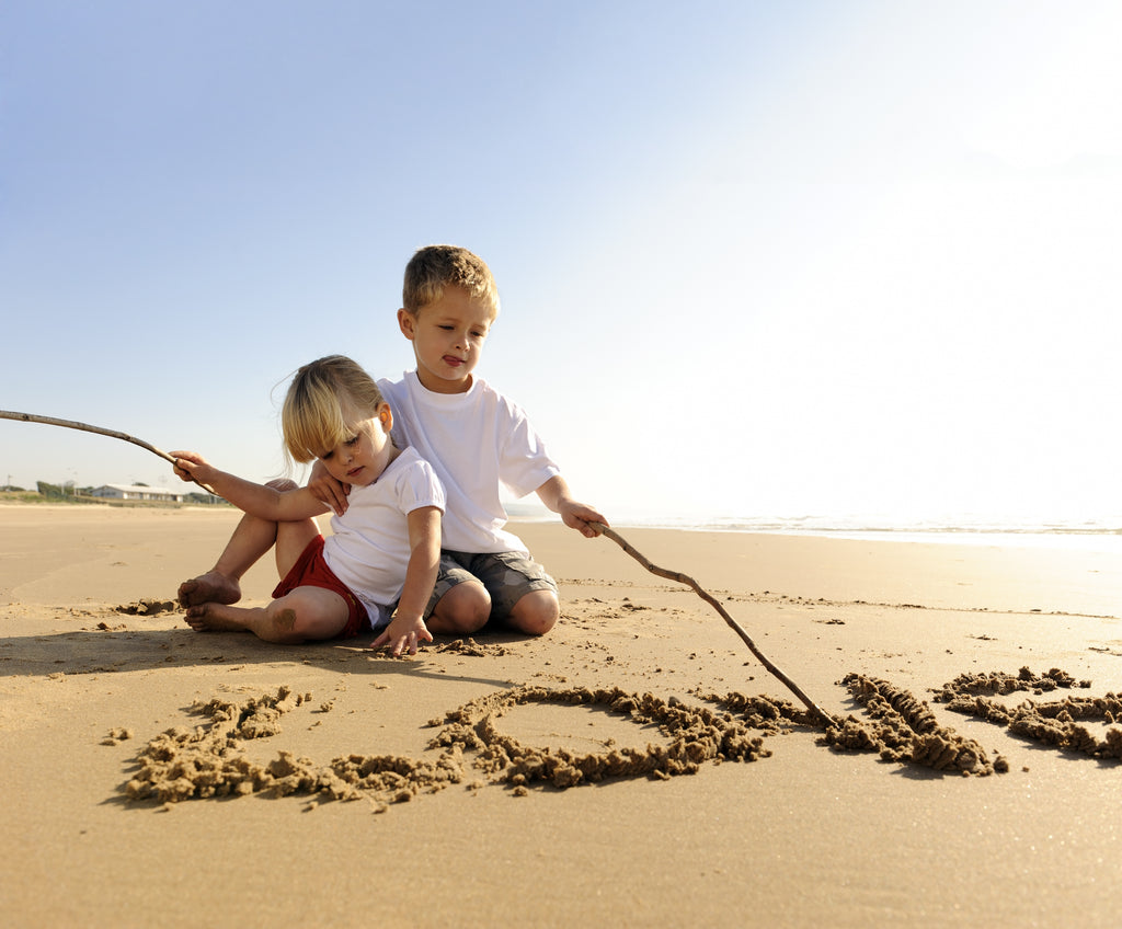 Beach photo of children writing the word love in the sand