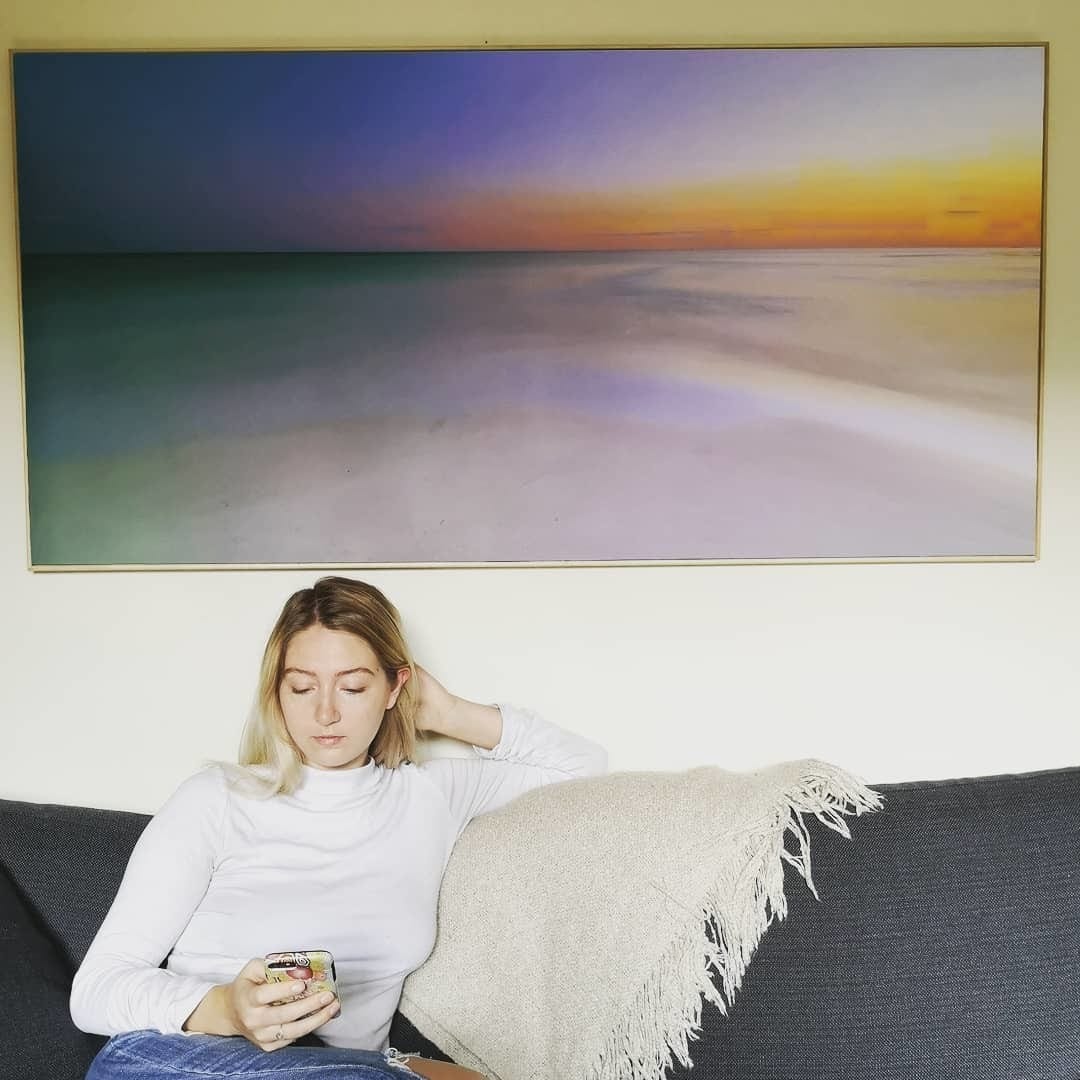 Posterjack customer sitting in front of her large photo print displayed on the wall.