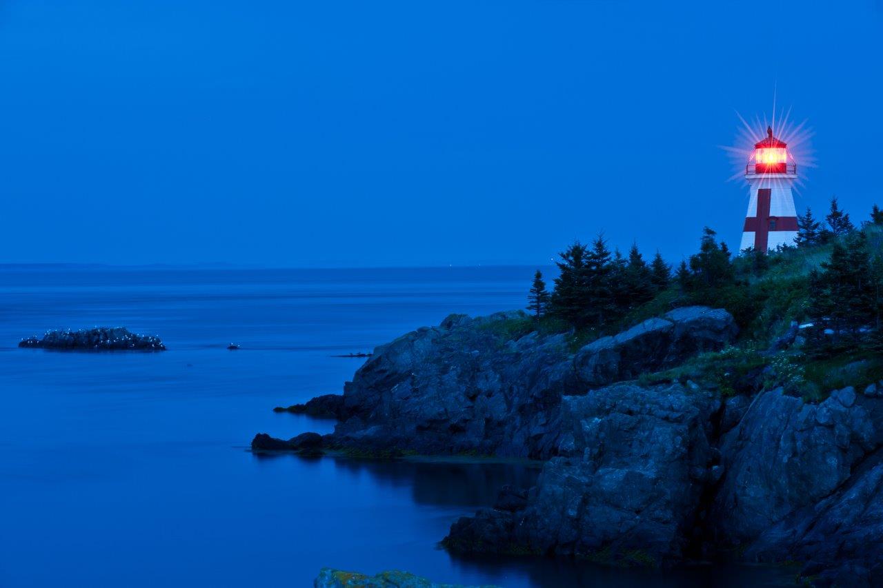 Lighthouse lit up at night - example of low-light photography without using a camera's flash