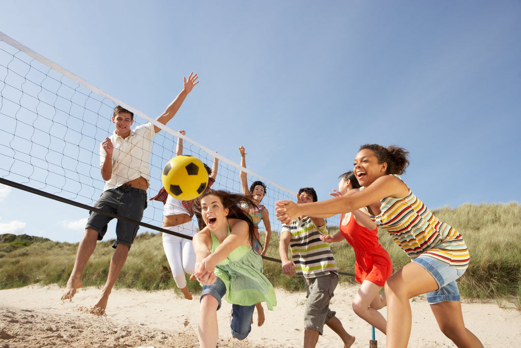 Candid beach photography of people playing volleyball in the sand