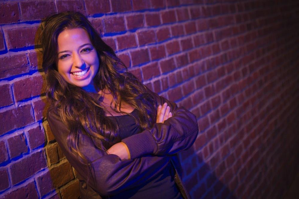 Portrait of a happy woman leaning against a brick wall - example of the rule of thirds in photography