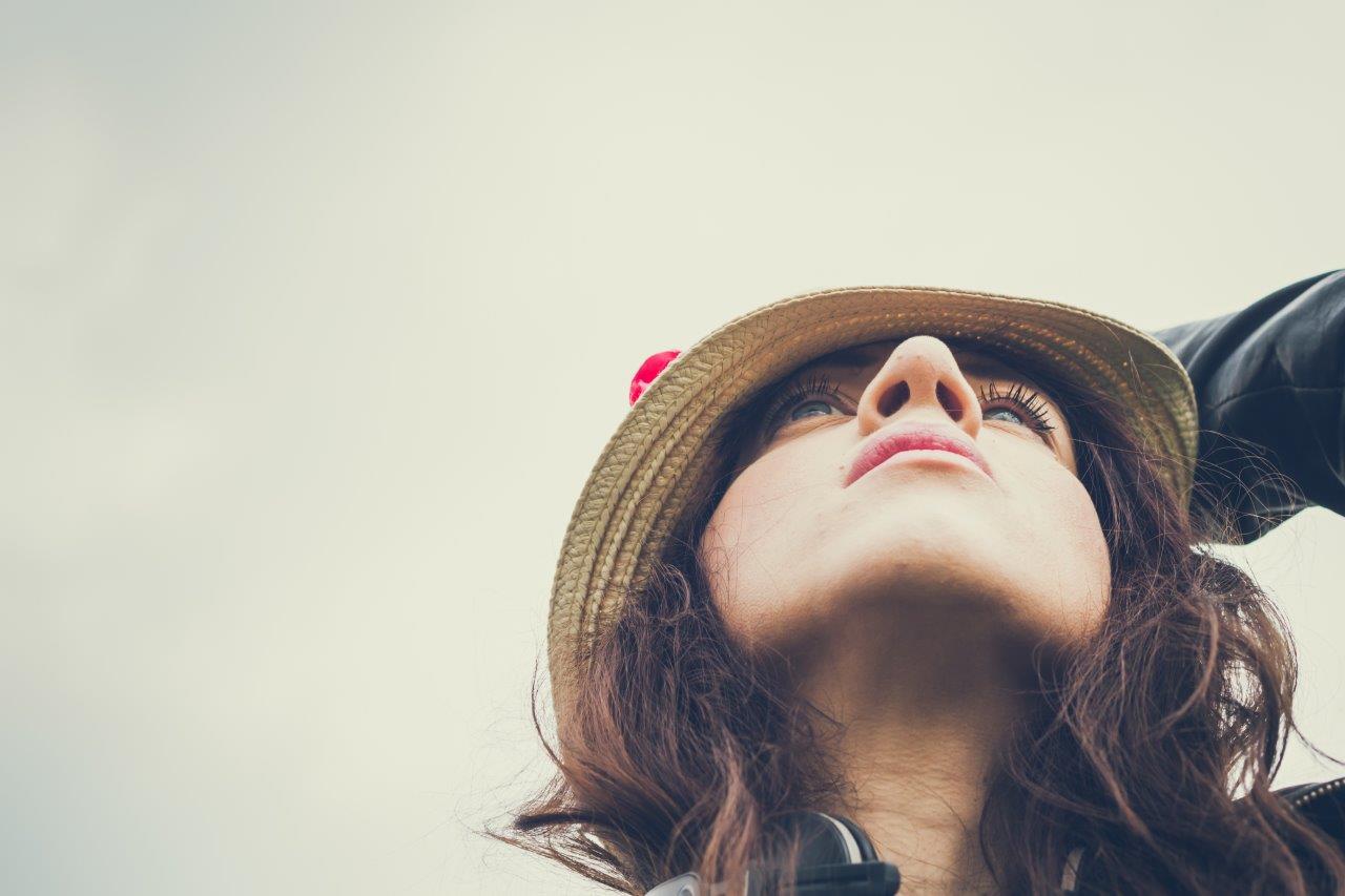 Portrait of a woman looking up with her hand on her hat