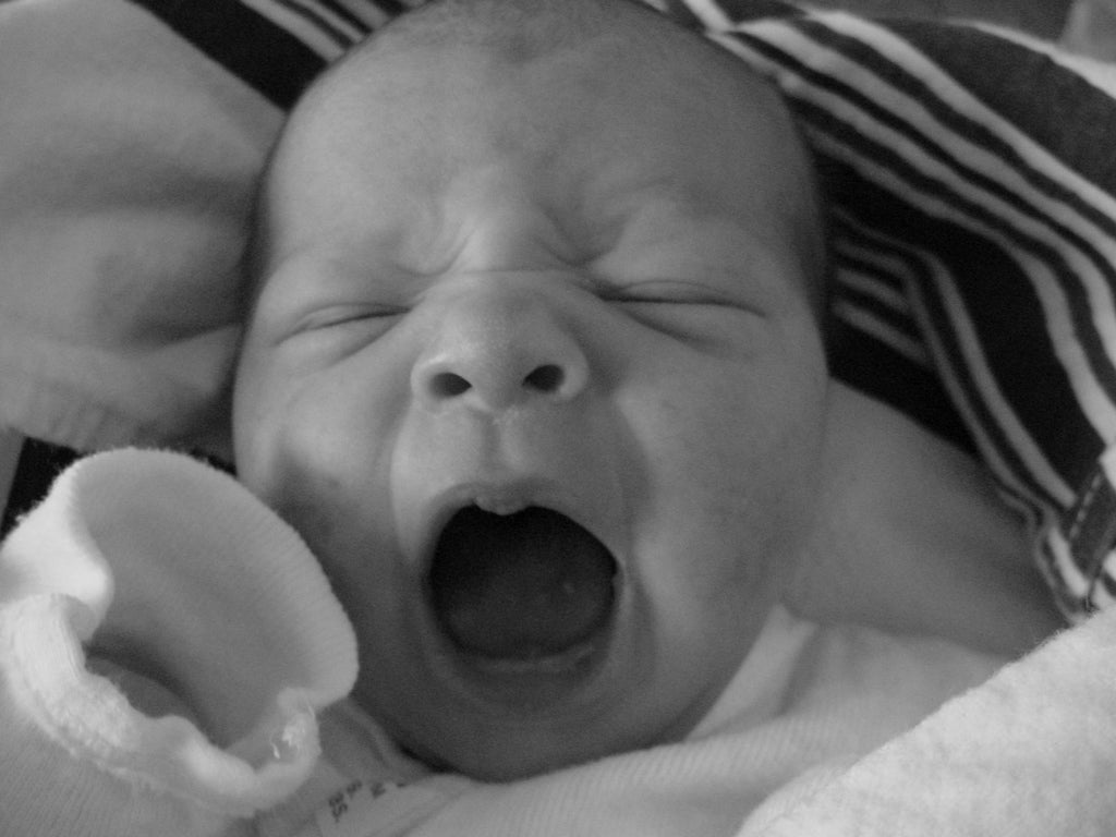 Black and white photo of a yawning newborn baby
