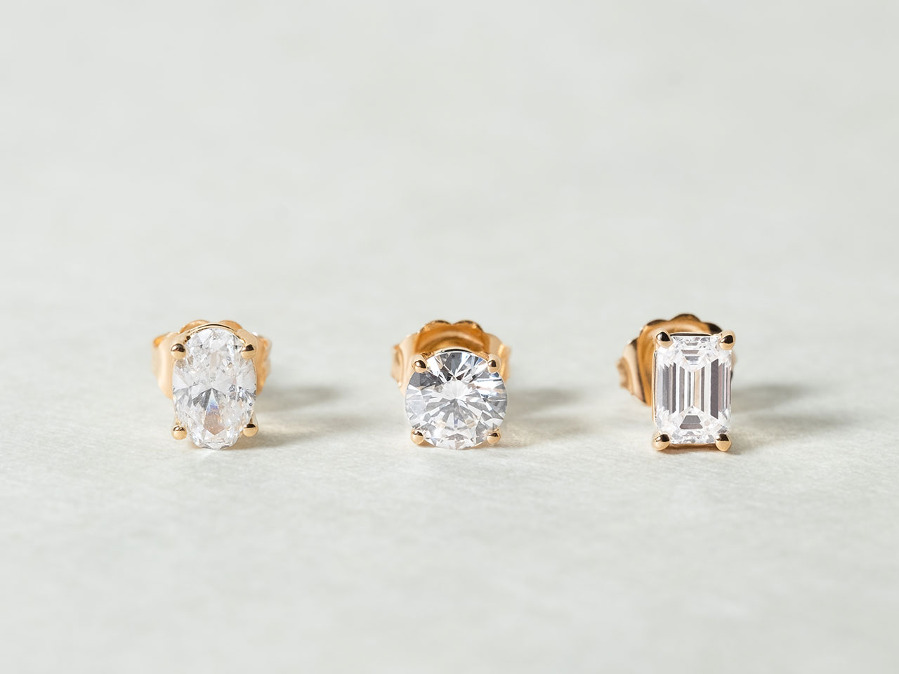 The Oval Diamond Stud, The Round Diamond Stud, and The Emerald Diamond Stud by Holden in yellow gold