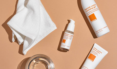 white bottles, white towel, and clear bowl in front of brown background