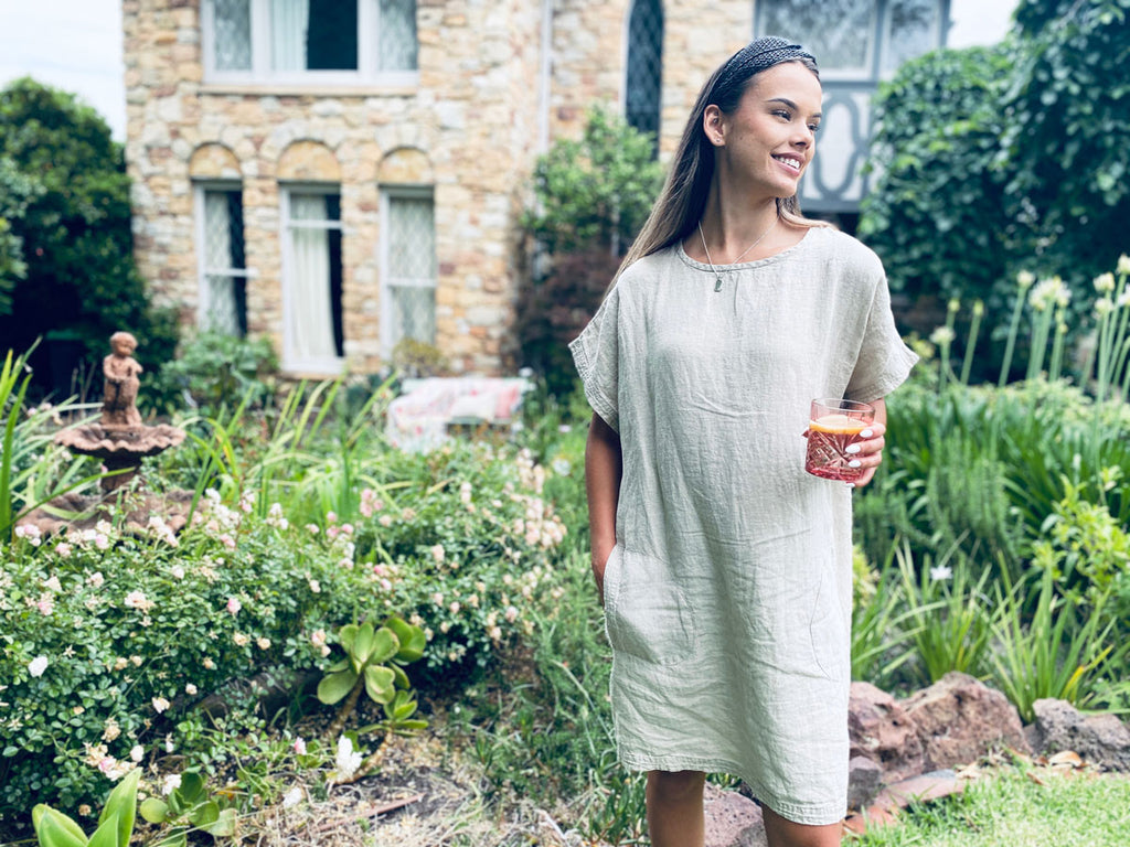 Woman standing in garden wearing the Eadie Lifestyle Pocket Linen Dress in natural