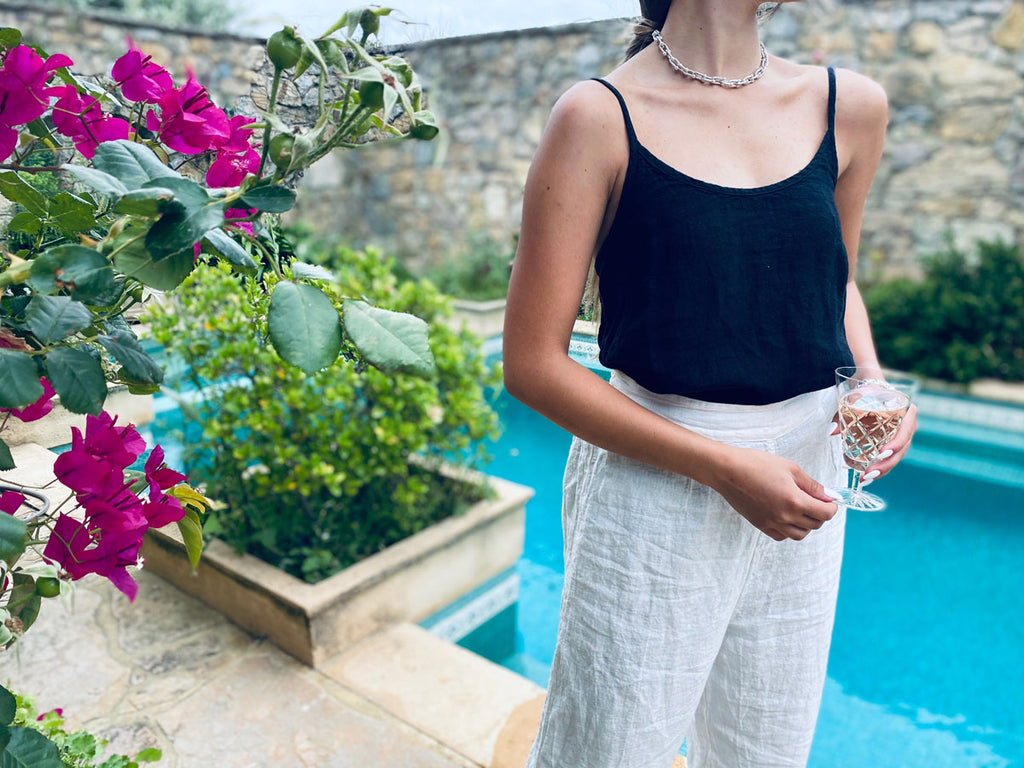 Woman wearing linen clothing standing in front of a pool