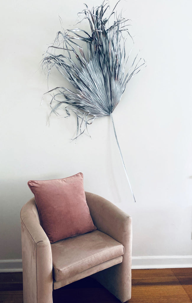 Palm leaf sprayed silver on the wall behind a pink velvet armchair with musk velvet Eadie Lynette cushion