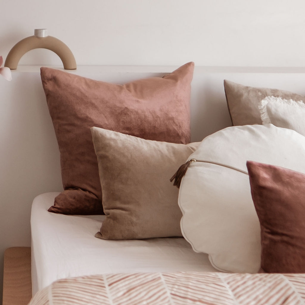 Velvet cushions in natural colours sitting on the bed