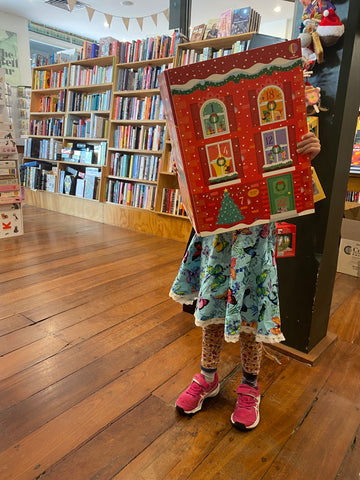 Child holding up an oversized Christmas book in New Edition bookshop