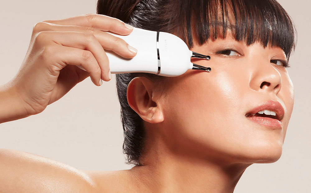 Woman using NuFACE trinity plus device to contour the face.