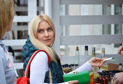 Woman making purchase looking over shoulder at friend as if asking a question