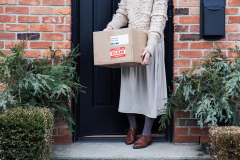 Woman picking up delivered package from doorstep