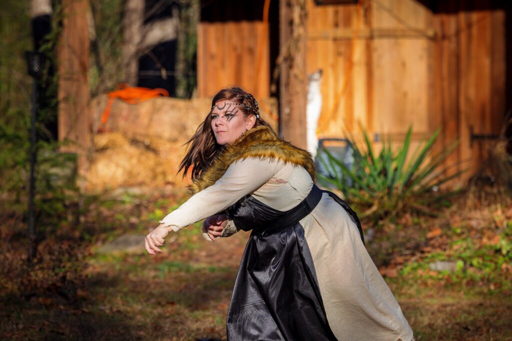 A woman in medieval costume throwing something 