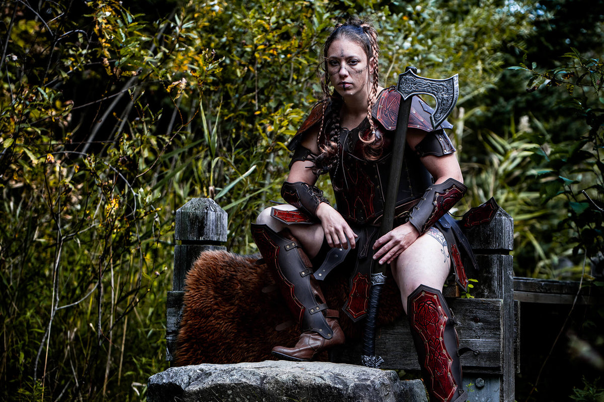 Larper in leather armor with a feet on a rock and holding an axe