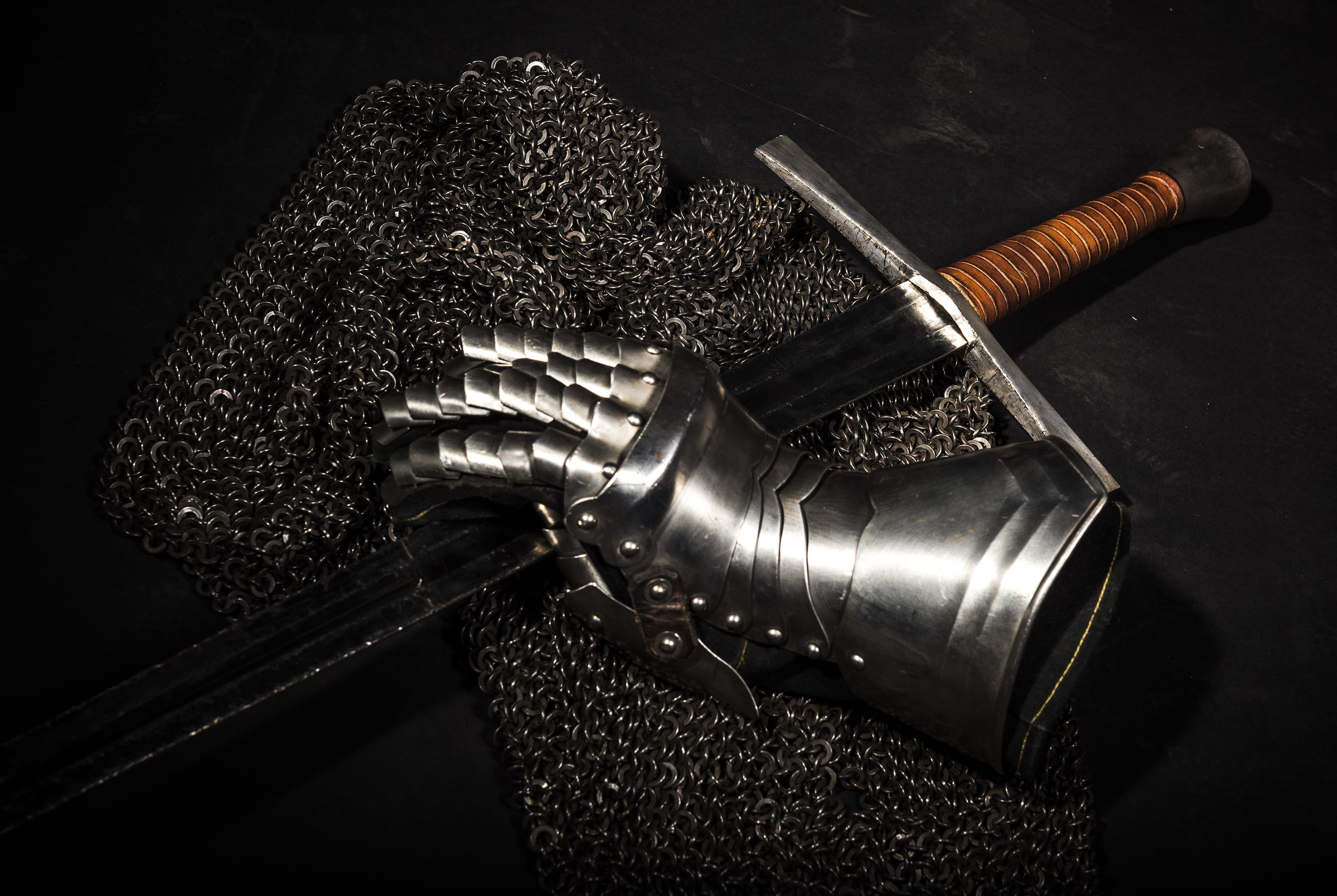 A steel sword and a metal gauntlet on chain mail 