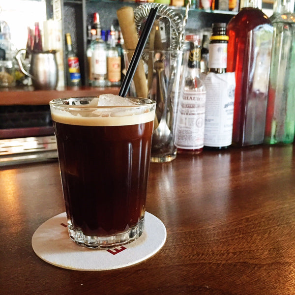 RISE nitro cold brew cocktail served in glass with straw at a bar
