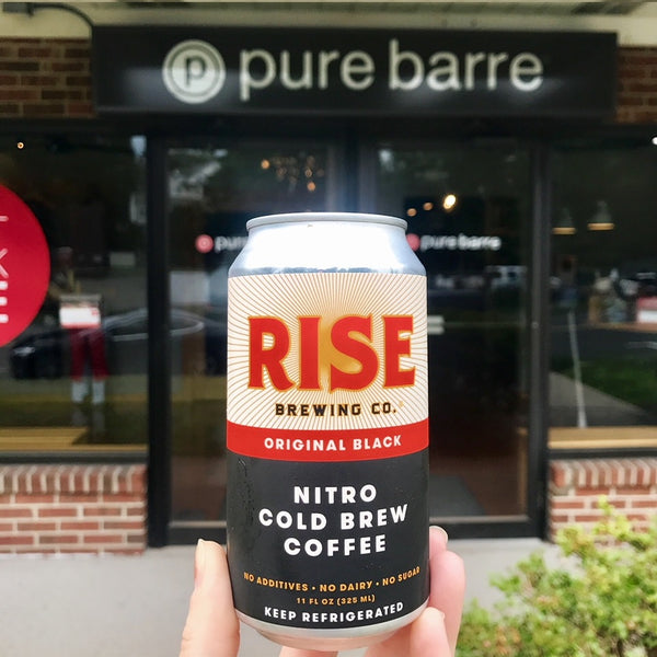 Organic, non-GMO RISE nitro cold brew coffee in a can in front of Pure Barre, fueling athletes and workouts