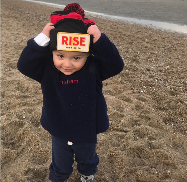 Baby with RISE Nitro Cold Brew Coffee hat on the beach