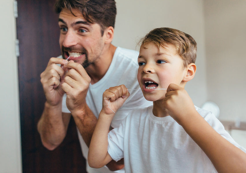 autistic child won't brush teeth. a boy is brushing his teeth with his dad. 