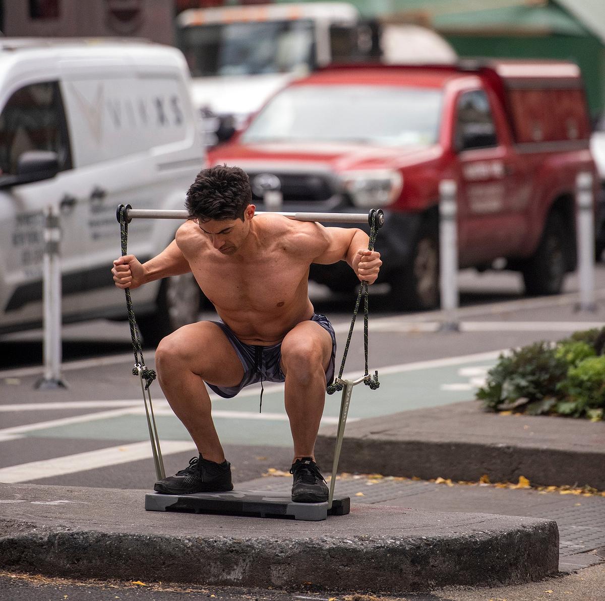 a gorilla is squatting in a gym with a barbell in front of him and